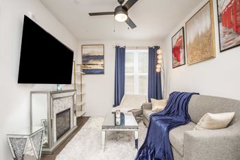 A living room with a grey couch, a fireplace, and a TV.